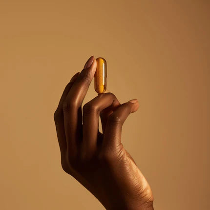 A daily supplement capsule held in morning light